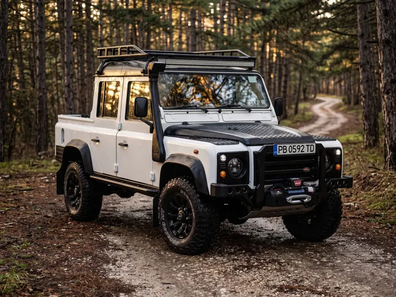 Defender 110 Crew Cab on a forest track in golden light