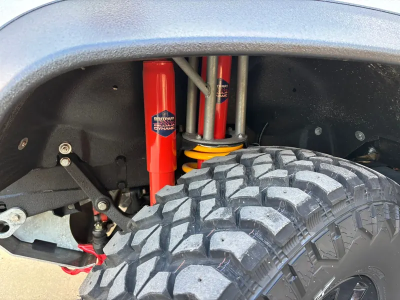 Red shock absorber and yellow spring above a Hankook mud-terrain tire